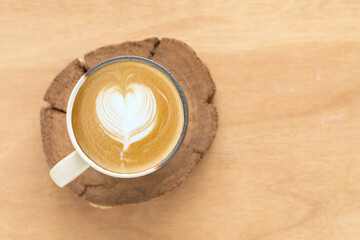 Top view, A cappuccino features latte art in the form of a heart, created with white foam in a white and brown speckled ceramic mug on wooden rustic. Concept for a banner, cafe, or coffee menu.
