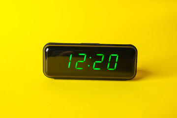 Digital alarm clock showing 12:20 o'clock on yellow background
