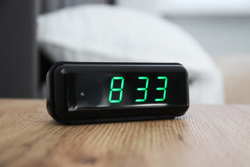 Digital alarm clock showing 8:33 o'clock on bedside table indoors