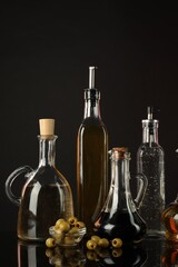 Obraz premium Salad dressings and olives on mirror surface against black background