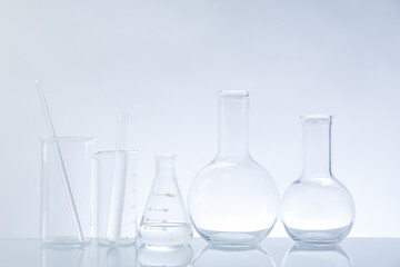 Laboratory glassware on mirror surface against light background