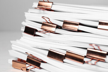 Binder clips with sheets of paper on table, closeup