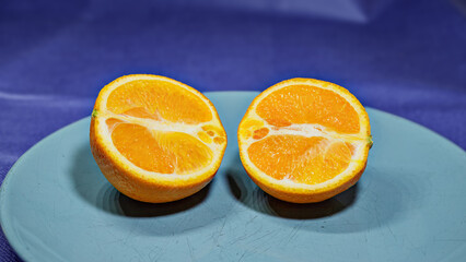 Fresh juicy orange citrus fruit slice isolated on a blue background and a blue plate.