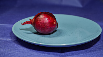 A red onion on a blue plate.