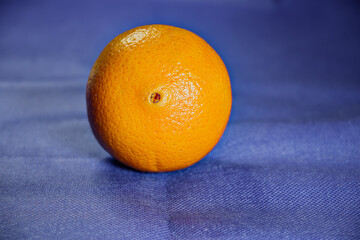 Fresh and juicy orange citrus fruit isolated on a vibrant blue and black background