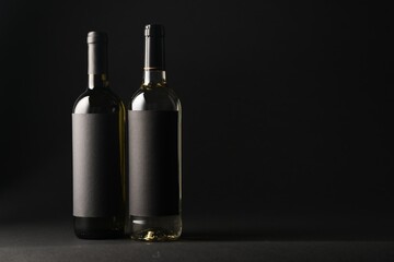 Bottles of wine on black background, space for text