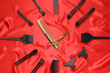 Clock made with hairdresser's tools on red fabric, flat lay