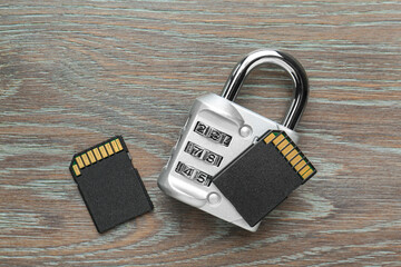 SD memory cards and combination padlock on grey wooden table, flat lay