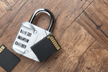 SD memory cards and combination padlock on wooden table, flat lay. Space for text