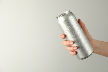 Woman with tin can on light grey background, closeup. Space for text