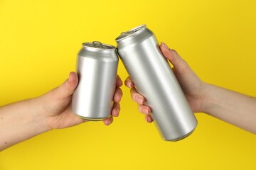 Women with tin cans on yellow background, closeup