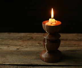 Burning candle in candlestick on wooden table, space for text