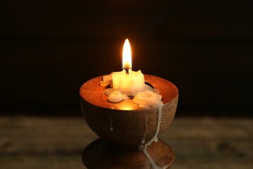 Burning candle in candlestick on table, closeup