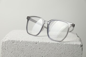 Stylish glasses on stone surface against light grey background, closeup