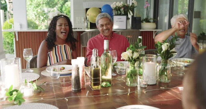 Diverse family enjoying meal together at beautifully set dining table with flowers, at home