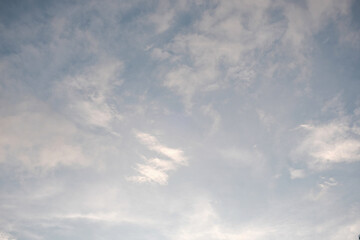 Wispy cirrus clouds scatter across a soft blue sky in the early morning, creating a light, airy backdrop with a calm and peaceful atmosphere.