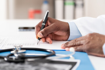 Close-up of doctor writing on paper or document at a desktop in the hospital.Healthcare...