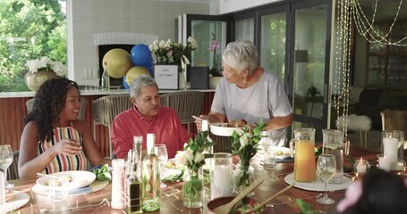 Diverse family enjoying meal together , sharing laughter and conversation at table, at home