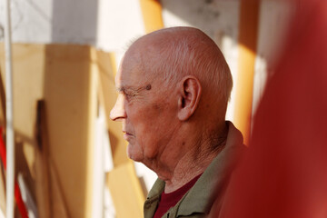 Elderly craftsman reflecting on years of artistry in a sunlit workshop filled with colorful...