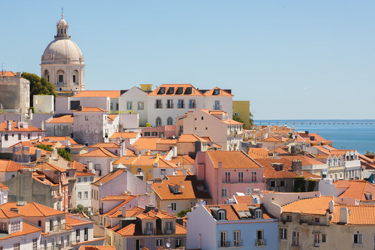 Church of Santa Engr&aacute;cia with iprominent dome overlooks picturesque Lisbon cityscape from Miradouro da Senhora do Monte,terracotta roofs, pastel buildings, and the Tagus waterfront in scenic old town.