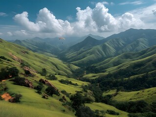 Fototapeta premium Scenic Mountain Valley: A breathtaking panorama unfolds as rolling green hills cascade towards distant mountains, crowned by a serene sky dotted with fluffy white clouds.
