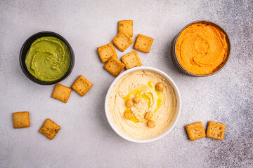 Various hummus dips in different colours. Hummus with dry crackers, top view. Vegan and traditional...