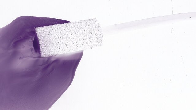 Purple Gloved Hand Holding White Porous Sponge Detail View