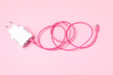 USB power adapter with charge cable on pale pink background, top view