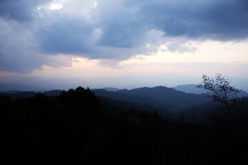 Beautiful sunset and silhouette on the valley mountain with dark cloud sky in Thailand