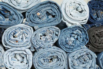 Different stylish rolled jeans as background, top view
