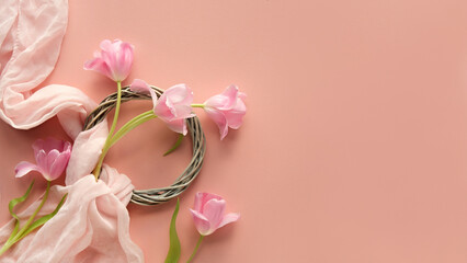 Pink tulips with a decorative wreath and soft fabric on a pastel pink background, with copy-space...