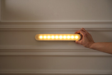 Woman turning on LED lamp at home, closeup