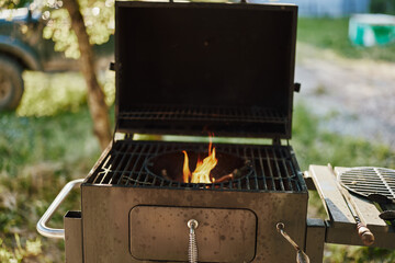 Outdoor grilling with a charcoal barbecue, lively flames and a natural green background, ideal for summer gatherings and barbecues