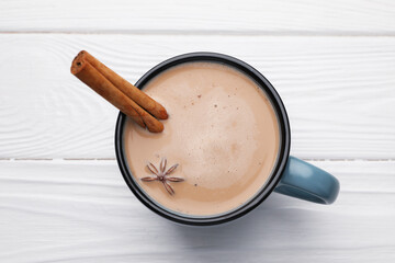 Aromatic Masala tea in cup, cinnamon and anise star on white wooden table, top view