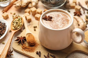 Aromatic Masala tea in cup, spices and brown on color textured table, closeup