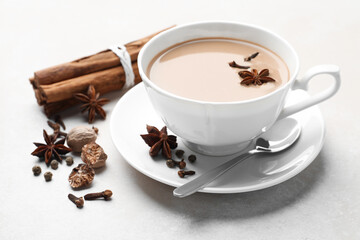 Aromatic Masala tea in cup and spices on light grey table, closeup