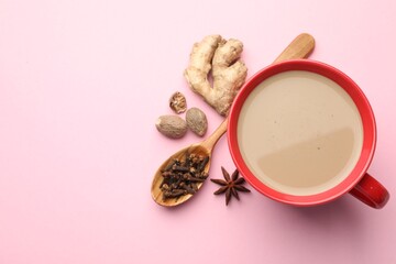 Aromatic Masala tea in cup and spices on pink background, flat lay. Space for text