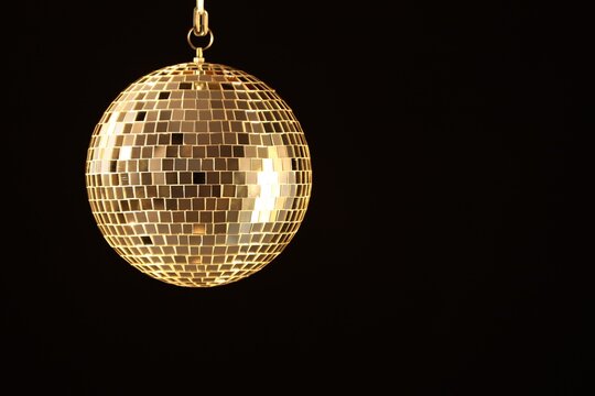 One shiny disco ball on black background, space for text