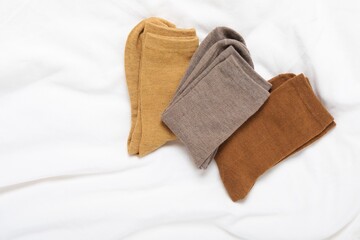 Different soft socks on white blanket, top view. Space for text