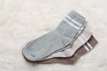 Different soft socks on white faux fur, top view
