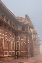 Obraz premium Foggy morning view of a red sandstone building with intricate Mughal-style architecture. Photo from Agra's Red Fort in India. UNESCO World Heritage Site. Vertical.