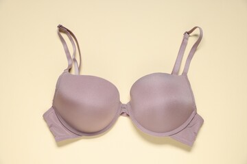One beautiful bra on beige background, top view