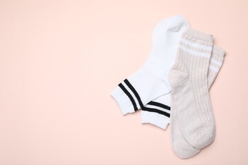 Pairs of socks on beige background, top view. Space for text