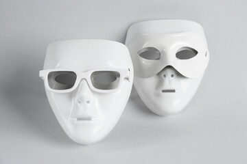 Plastic theatre masks with sunglasses on light grey background