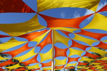 Outdoor decoration for event celebration. Colorful pennants in vibrant yellow and red colors against a blue sky on a sunny day.