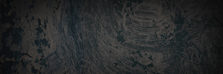 Dark wide panoramic background. Peeling paint on a concrete wall. Dark grunge texture of old cracked flaking paint. Weathered rough painted surface. Patterns of cracks. Darkness background for design.
