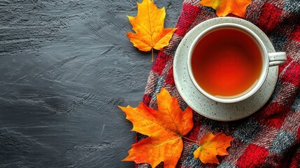 Cup of tea surrounded by autumn leaves on a black background for cozy fall picnic flat lay