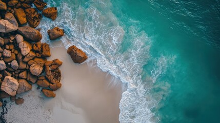 Fototapeta premium Aerial view turquoise ocean waves lapping rocky beach, sunset