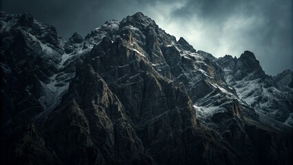 Obraz premium Dark rocky mountain landscape with light patches of snow under moody overcast sky in cold gloomy atmosphere