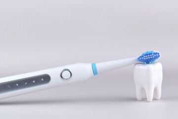 Modern electric ultrasonic toothbrush with rechargeable battery on a gray surface.
